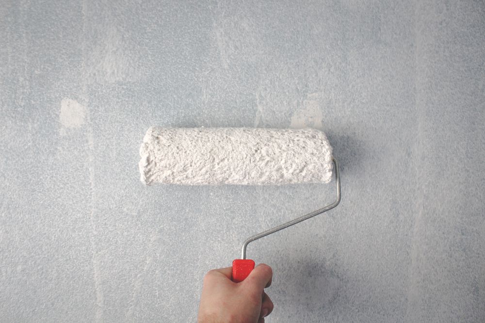 Close-up of a paint roller applying a smooth coat to a wall